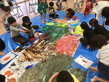 ワークショップ参考画像　大きな絵を描く子どもたちの様子（画像提供：小池アミイゴ）