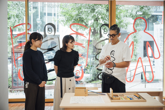 RAW05 ケア×アート ボディーズ!!　ワークショップ「オルガニートで奏でる 『からだ』の記憶」の様子。池上恵一が、参加者2名にワークショップの説明をしている。